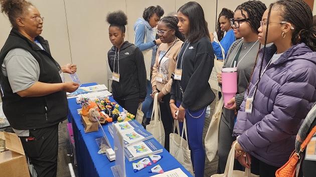 TOP PHOTO: Homewood Science Center’s 2024 Girls STEAM Celebration, held in mid-April, drew students from 24 middle and high schools from the greater Chicago area. 一群学生站在活动台