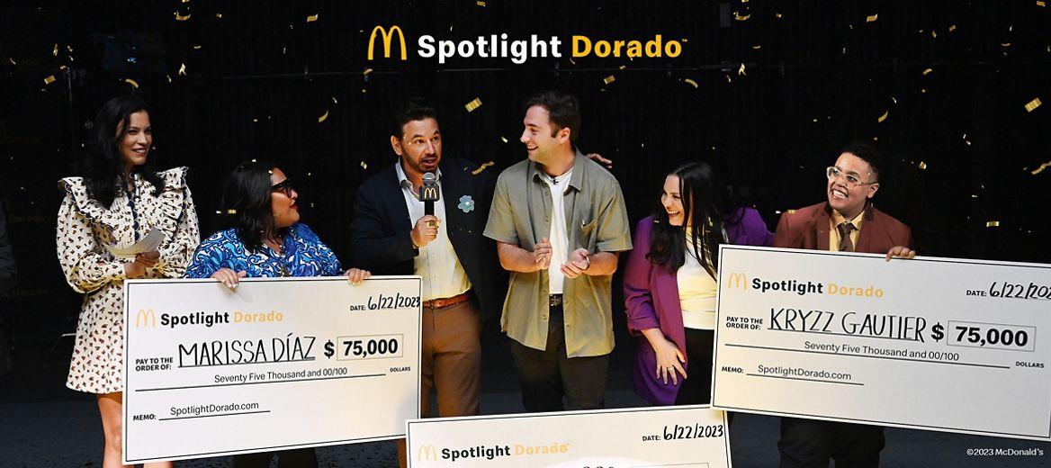 麦当劳的标志和“聚光灯Dorado”上面三个获奖者和主持人拿着大检查五彩纸屑。